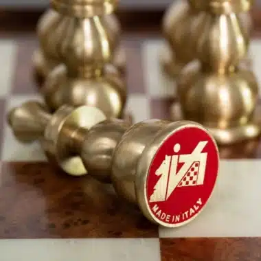 Détail d'un pion en laiton renversé sur l'échiquier, médaillon rouge gravé