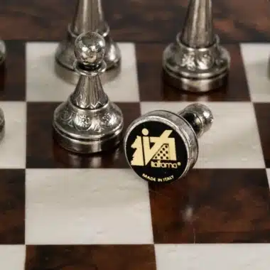 Pion en métal couché, détail de la base feutrée sur échiquier en bois