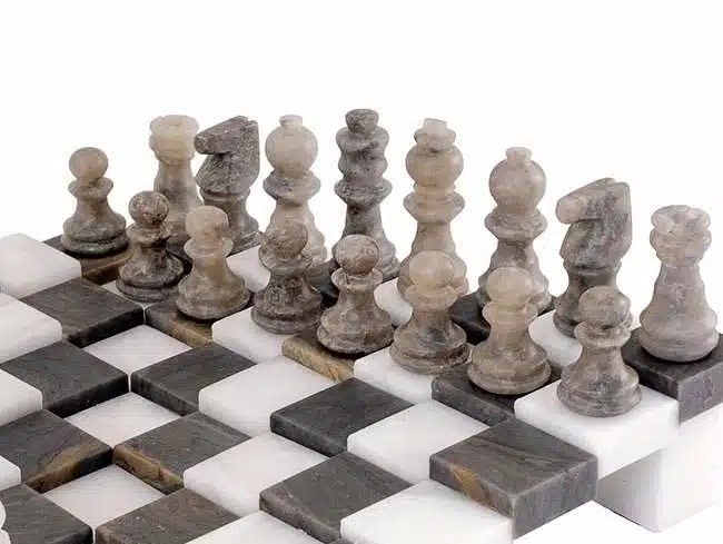 Pièces d'échecs en marbre gris alignées sur l'échiquier 3D antique