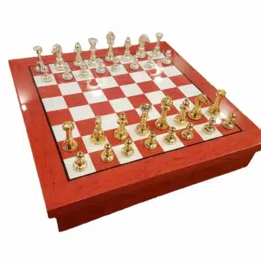 Échiquier rouge et blanc en bois avec pièces en laiton doré et argenté disposées en partie