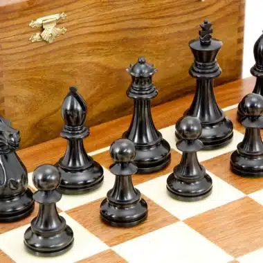 Détail des pièces noires sculptées, roi, dame et pions, sur l'échiquier en bois