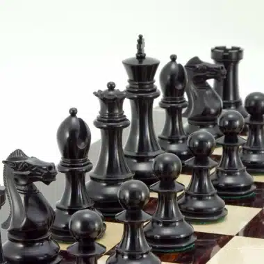 Pièces d'échecs noires en ébène posées sur un échiquier en marqueterie